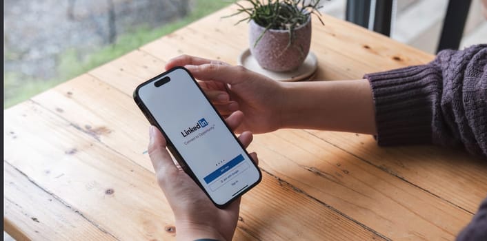 CHIANG MAI, THAILAND, JUL 7, 2023 : A women holds Apple iPhone 14 with LinkedIn application on the screen. LinkedIn is a photo-sharing app for smartphones..