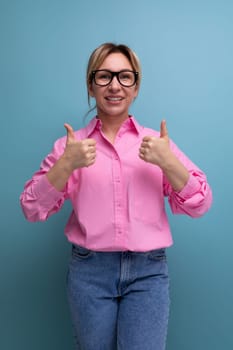 young confident stylish blond businesswoman in glasses is dressed in a pink shirt and jeans.