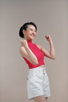 Happy successful young asian female with raised hands celebrating success
