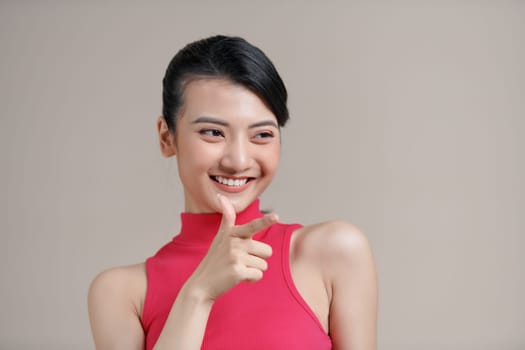 Young beautiful brunette businesswoman smiling looking at camera pointing finger in side over white background.