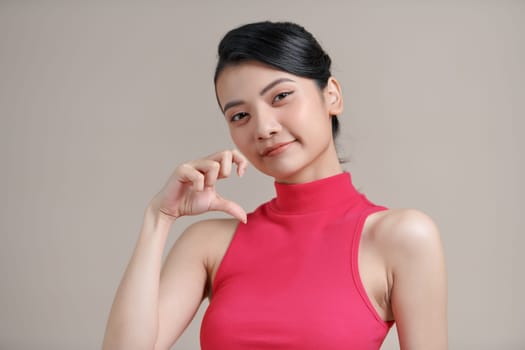 Young beautiful woman smiling in love doing heart symbol shape with hands.