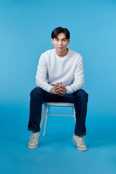 Photo of young guy smiling sitting chair empty space isolated blue color background