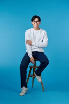 Happy smart casual man smiling with his hands folded while sitting on a chair 