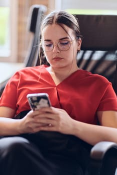 A businesswoman resting on a short break from work in a modern startup coworking center, using her smartphone to unwind and recharge