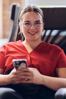 A businesswoman resting on a short break from work in a modern startup coworking center, using her smartphone to unwind and recharge