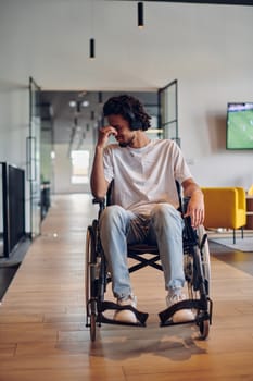 A sad businessman in a wheelchair occupies a hallway within a modern startup coworking center, embodying inclusivity and determination in the business environment.