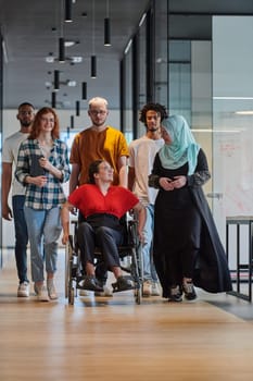 A diverse group of young business people walking a corridor in the glass-enclosed office of a modern startup, including a person in a wheelchair and a woman wearing a hijab, showing a dynamic mix of innovation and unity