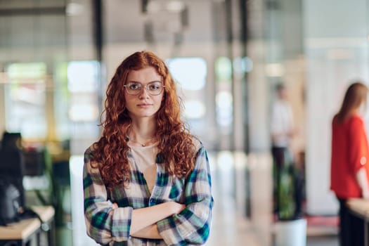 A portrait of a young businesswoman with modern orange hair captures her poised presence in a hallway of a contemporary startup coworking center, embodying individuality and professional confidence