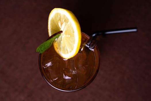 cold alcoholic drink with ice and a slice of lemon in a glass glass with a straw.