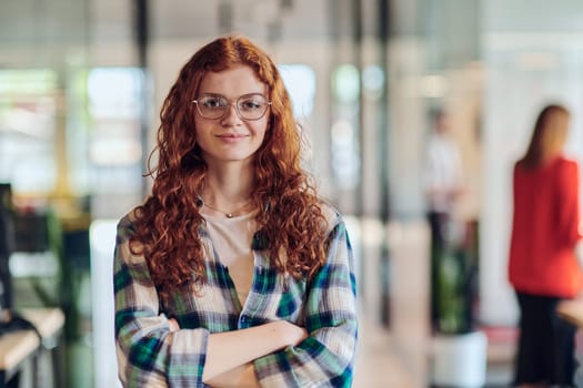 A portrait of a young businesswoman with modern orange hair captures her poised presence in a hallway of a contemporary startup coworking center, embodying individuality and professional confidence