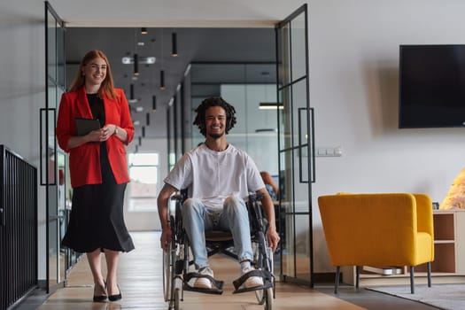 A group of young business people in a modern glass-walled office captures the essence of diversity and collaboration, while two colleagues, including an African American businessman in a wheelchair, reflect inclusivity and discuss solving business problems.