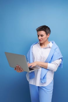european young brunette woman with tousled hair works remotely using laptop.