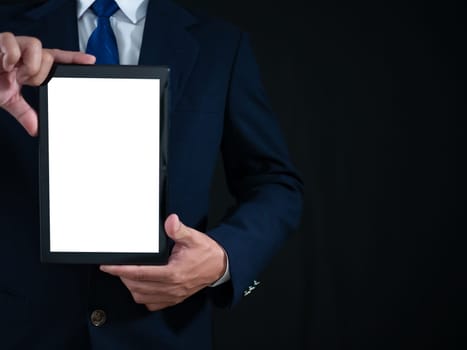 Businessman standing holding white screen tablet on dark background. Advertising concept. Banner sign.