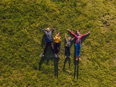 family top view. lying on the grass. sunny day. in green nature together. Aerial view Drone photography.