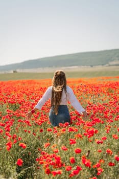 Woman poppies field. Back view of a happy woman with long hair in a poppy field and enjoying the beauty of nature in a warm summer day