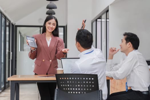 Professional businesswomen presenting to colleagues in conference room explaining corporate earnings..