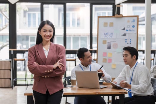 Portrait of a young businesswoman standing in an office where employees are working..