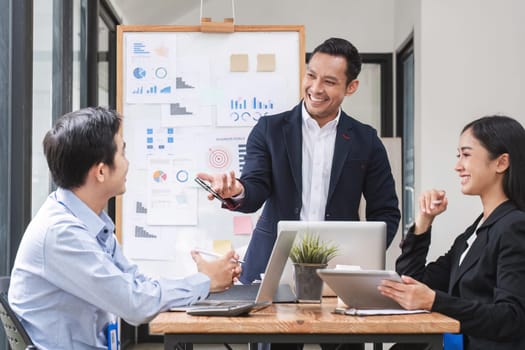 Professional businessman presenting to colleagues in conference room explaining growth chart.