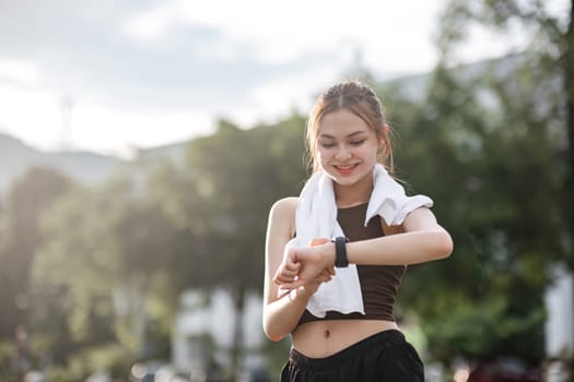 Young woman jogging and looking at his smart watch in the evening at the park..