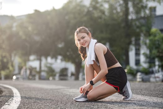 Portrait of a young woman tying her shoes to prepare for exercise..