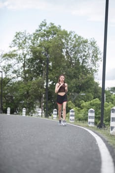 Young sporty woman jogging in the green park in the evening.