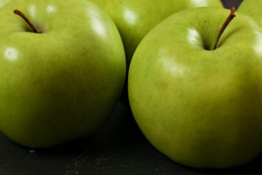 Green apples on black board - closeup photo with detail on skin texture.