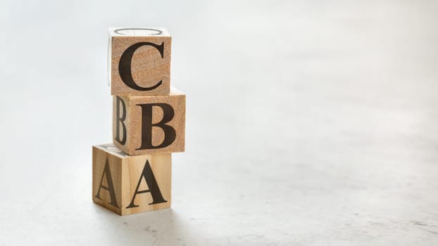 Pile with three wooden cubes - letters CBA meaning Cost Benefit Assessment on them, space for more text / images at right side.