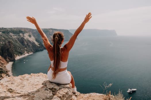 Middle aged well looking woman with black hair doing Pilates with the ring on the yoga mat near the sea on the pebble beach. Female fitness yoga concept. Healthy lifestyle, harmony and meditation.