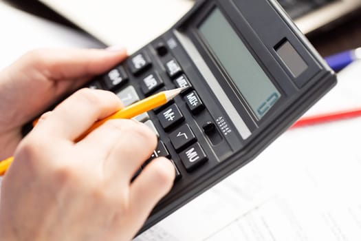 Woman managing household family expenses using calculator, calculating household finances or car taxes.