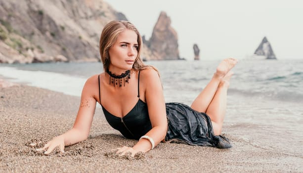 Woman travel sea. Young Happy woman in a long red dress posing on a beach near the sea on background of volcanic rocks, like in Iceland, sharing travel adventure journey