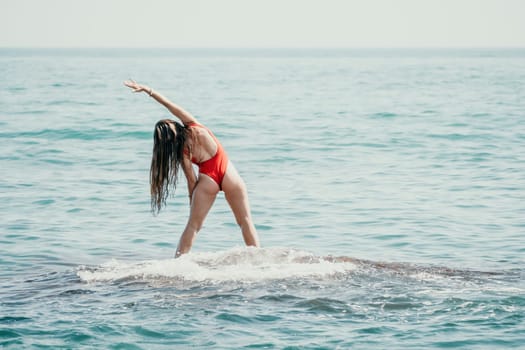 Woman sea yoga. Back view of free calm happy satisfied woman with long hair standing on top rock with yoga position against of sky by the sea. Healthy lifestyle outdoors in nature, fitness concept.