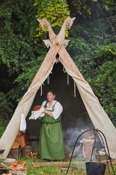Hojbjerg, Denmark, July 29, 2023: The hostess rubs the plate in the tent at the Viking Festival.
