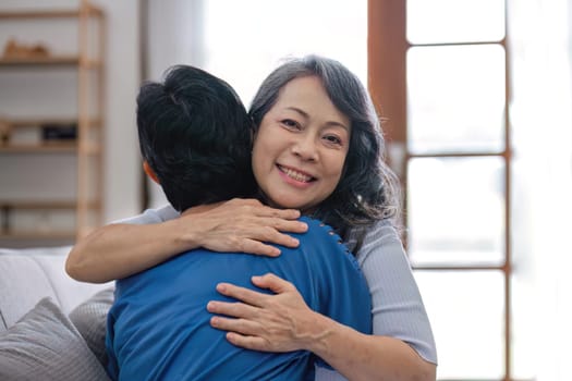 Two retired Asian women hug as they meet and have fun in the living room..