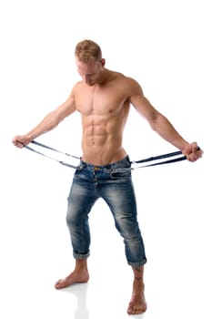 A shirtless man holding a pair of suspenders, looking down in a studio setting