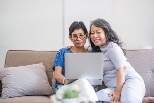 two 60s woman enjoy with social media on her laptop on a sofa.