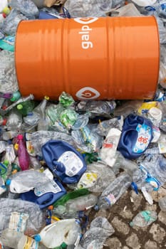 16 october 2022 Almada, Portugal: GALP orange barrel laying on top of plastic garbage. Vertical shot