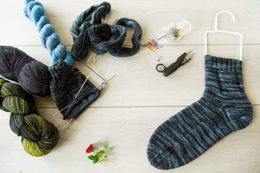 Set for hand knitting warm winter socks made of natural woolen yarn, on a wooden table.