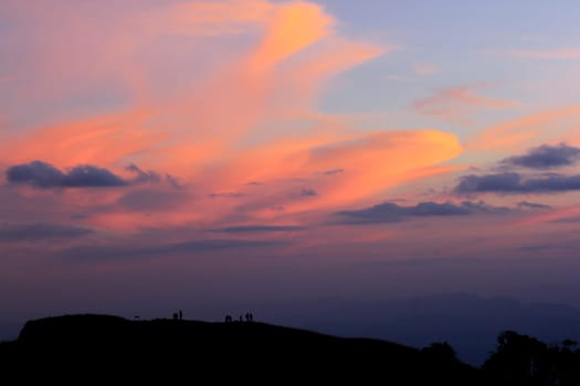Silhouettes of people standing on the summit.