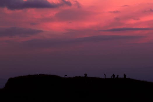 Silhouettes of people standing on the summit.