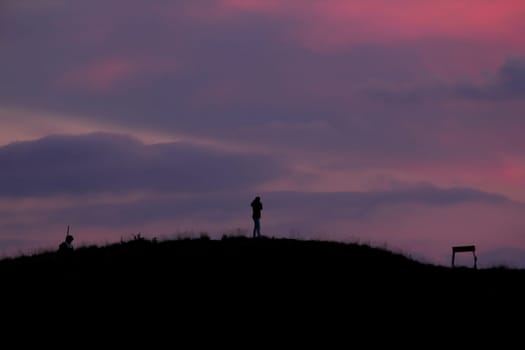 Silhouettes of people standing on the summit.