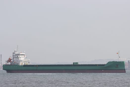 A large industrial barge in a Portuguese river. Mid shot