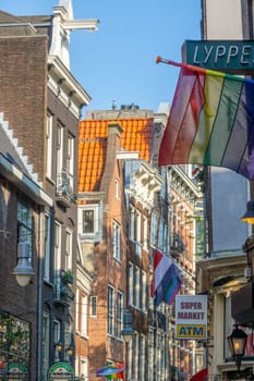 Netherlands. Summer sunny day in Amsterdam. Typical facades and roofs of houses on a narrow street in the city center. Lots of flags and advertising signs