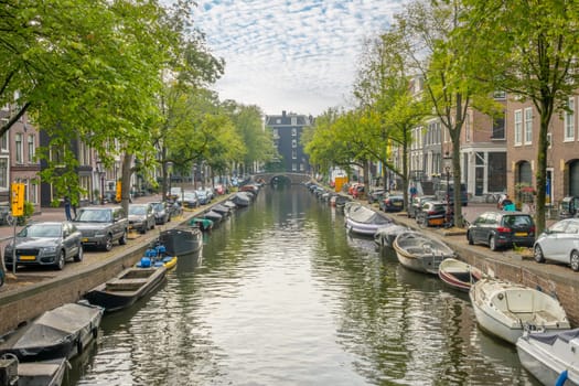 Netherlands. Summer day on the canal in the center of Amsterdam. Lots of moored boats. Lots of parked cars on the banks of the canal