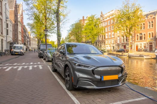 Netherlands. Sunny summer day on the banks of the canal in Amsterdam. Electric supercar charging on the waterfront