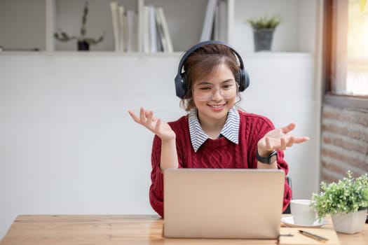 Asian female student study online in class, study online, wearing headphones, watching video call, zooming, happy asian female learning language online with computer laptop