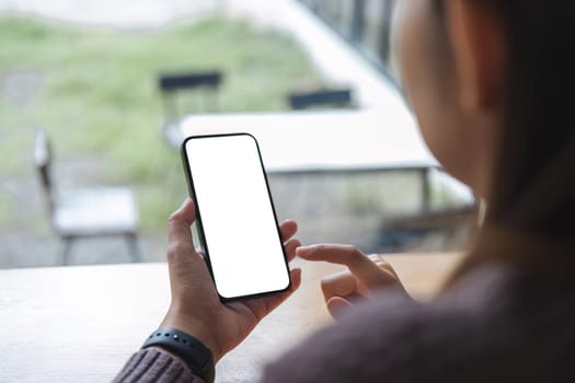 Mockup image of closeup woman hand holding mobile phone with blank white smartphone screen at the outdoor..