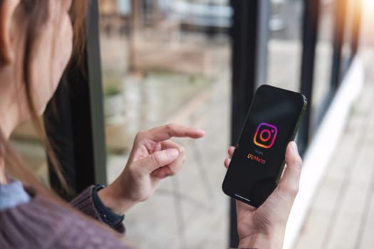 CHIANG MAI, THAILAND - JUL 7, 2023: A woman holds Apple iPhone X with Instagram application on the screen at cafe. Instagram is a photo sharing app for smartphones..