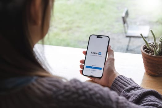 CHIANG MAI, THAILAND, JUL 7, 2023 : A women holds Apple iPhone 14 with LinkedIn application on the screen. LinkedIn is a photo-sharing app for smartphones..