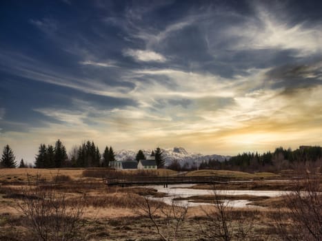 A field with a house and trees in the background. Photo of a picturesque field with a charming house and majestic trees in the breathtaking landscape of Iceland