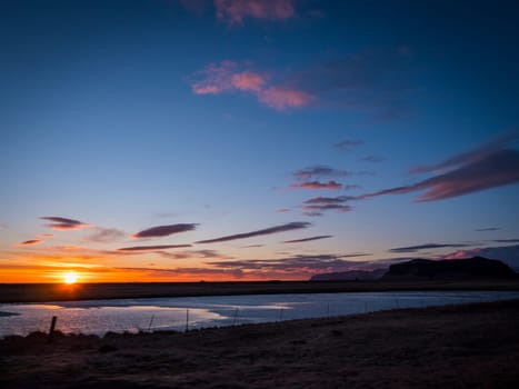 The sun is setting over a body of water. Photo of a beautiful sunset over a serene Icelandic body of water